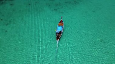 Tayland 'da Koh Kradan' ın turkuaz sularını, kristal berrak denizde süzülen geleneksel bir uzun kuyruklu tekne olarak deneyin. Dokunulmamış doğaya ve sakin çevreye hayret.