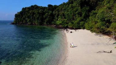 Tayland, Koh Kradan 'ın nefes kesici güzelliğini keşfedin. İki maceracı el değmemiş plajda gezinirken. Berrak sular ve yemyeşil yeşil cennet gibi tropikal bir kaçış yaratır..