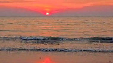 Krabi Tayland 'da huzurlu bir sahilde güneş ufkun altına batarken nefes kesici günbatımına tanık olun. Canlı renkler sakin sulara güzel bir şekilde yansıyor, sakin bir atmosfer yaratıyor..