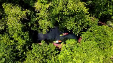 Krabi Tayland 'da canlı yeşilliklerle çevrili sakin su yollarından geçen bir çift. Sakin sularda gezinirken doğanın güzelliğini hissedin ve huzurlu atmosferin tadını çıkarın..
