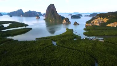 Phangnga Körfezi 'nin eşsiz kaya oluşumları ve canlı yeşil mangrovlarının nefes kesici manzaraları. Gün batımında bu çarpıcı sahil cennetinin doğal güzelliğini ve sükunetini keşfedin..