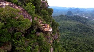 Macera meraklıları Krabi Tayland 'da uçurumun kenarında, yemyeşil manzaralar ve uzak dağlar, Khao Ngon Nak' ın büyüleyici panoramik manzarasına tanık olurken heyecana tanık olun.