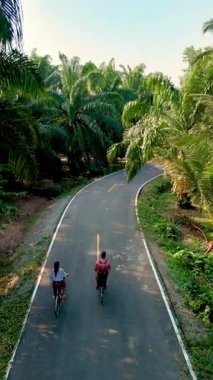 İki bisikletçi Chumphon Tayland 'da manzaralı, dolambaçlı bir yolda giderken macera bizi bekliyor. Uzun palmiye ağaçları ve canlı yeşilliklerle çevrili bu yolculuk doğanın güzelliğini ve keşiflerini somutlaştırıyor..