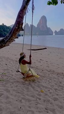 Tayland, Krabi 'nin sakin güzelliğini hissedin. Yumuşak kumda salıncaktan hoşlanan bir kız gibi. Etrafı çarpıcı kireçtaşı uçurumları ve kristal berrak sularla çevrili..