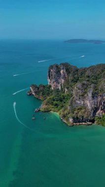 Tayland 'daki Tonsai Krabi' nin nefes kesici kıyı şeridi boyunca turkuaz sularının yemyeşil tepelerle buluştuğu yerde. Tekneler denizde usulca süzülüyor, bir ada cennetinde güzellikler sergiliyor..