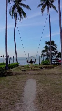 Tayland, Krabi 'deki çarpıcı bir plajın arka planında sevinçle sallanan bir kişi olarak sakin bir akşam başlıyor. Palmiye ağaçları rüzgarda hafifçe sallanıyor..