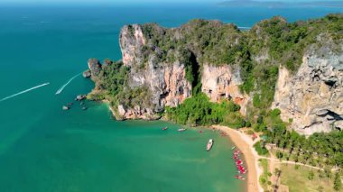 Turkuaz suların yükselen kireçtaşı kayalıklarla buluştuğu Krabi Tayland 'ın nefes kesici manzarasını deneyin. Huzurlu atmosferin tadını çıkarırken tekneler ve sahile gidenler cennetin tadını çıkarıyorlar..