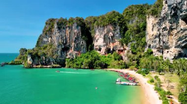 Tonsai plajı Krabi Tayland 'ın güzelliğini yaşayın. Canlı turkuaz suların yükselen kayalıklarla buluştuğu yer. Tekneler kıyı şeridini doldurur, keşifleri davet eder, palmiye ağaçları rüzgarda hafifçe sallanırken.