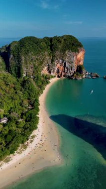Krabi Tayland 'da çarpıcı kıyı şeritlerini ve yemyeşil alanları keşfedin. Sakin atmosfer ve canlı manzaranın tadını çıkarırken yumuşak kumlu sahillerde rahatlayın. Railay Sahili insansız hava aracı Kireçtaşı görüntüsü