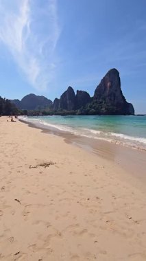 Tayland 'da, Railay Beach Krabi' de hafif dalgalar kıyıya vururken beyaz kumlar parlak bir gökyüzünün altında uzanıyor. Yükselen kireçtaşı kayalıkları çarpıcı manzarayı çerçeveletip keşif yapmaya davet ediyor..