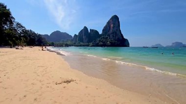 Krabi Tayland 'ın güzelliğini tecrübe edin. Güneş banyosu altın kumlarda dinlenirken ve turkuaz sular açık mavi gökyüzünün altında parıldarken. Railay Sahili Tayland