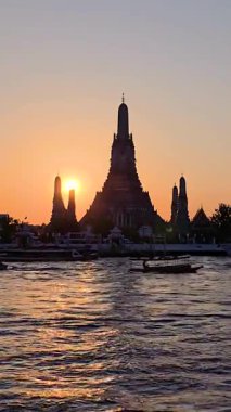 Güneş, Bangkok 'taki ikonik Wat Arun' un arkasında batarken alacakaranlığın canlı renkleri karmaşık mimariyi aydınlatıyor..