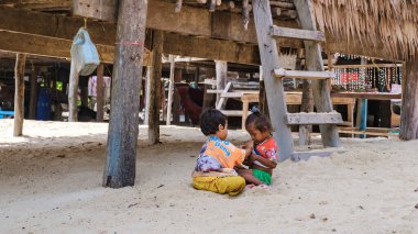 Phangnga, Tayland, 21 Ocak 2025, Surin Adası 'nda geleneksel bir barınağın altındaki kumlu zeminde oynayan yerel Moken çocukları ada yaşamının ve yerel kültürün basitliğini gözler önüne seriyor..