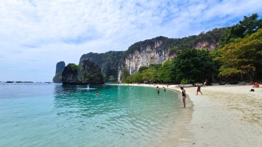 Koh Hong Adası Krabi Tayland 26 Ocak 2025, insanlar berrak turkuaz sularda yürürken yumuşak bir güneşin altında güneşleniyorlar. Bereketli kayalıklar ve canlı yeşillikler resim gibi bir zemin oluşturur..