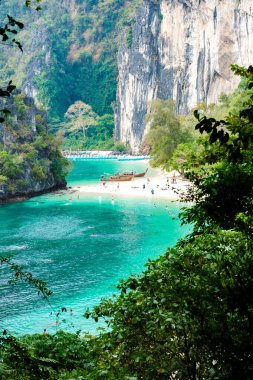 Koh Hong Adası Tayland 'da, yüksek kireçtaşı uçurumları tarafından kucaklanan sakin turkuaz sulara sahip ziyaretçiler sıcak güneşin altındaki sakin sahil manzarasının keyfini çıkarıyorlar.. 