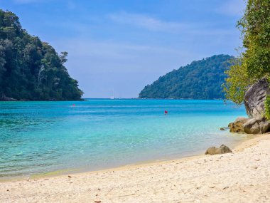 Gök mavisi suların ziyaretçileri keşfetmeye davet ettiği Tayland Surin Adası 'nın çarpıcı plajları yemyeşil tepelerle çevrilidir..