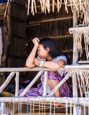 Phangnga, Tayland, 21 Ocak 2025 'te genç bir Moken kadını, Surin Adası' nın yemyeşil yeşillikleriyle çevrili ahşap bir balkonda derin derin oturur.