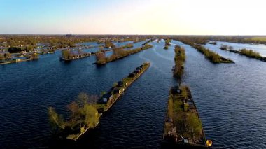 Güneş batarken Hollanda 'nın çarpıcı su yollarını keşfedin, dingin mahalleler üzerine sıcak bir parıltı saçın ve manzarayı süsleyen yemyeşil alanlar. Vinkeveense Plassen Hollanda