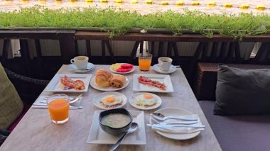 Taze meyve, hamur işi, yumurta ve yerel yemeklerle Bangkok 'ta canlı bir kahvaltı yapın. Büyüleyici kafe, Wat Arun tapınağında yemyeşil ve şehir manzaralı rahatlatıcı bir atmosfer sunuyor.