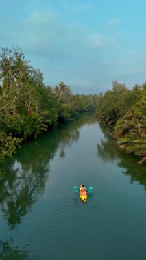 Chumphon Tayland 'da canlı yeşilliklerle çevrili sakin sularda kürek çek. Yağmur ormanlarında kanodaki bir çift.