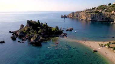 Isola Bella plajı Taormina Sicilya 'nın göz kamaştırıcı sahil şeridini keşfedin. Kristal berrak suların huzurlu kumsallarla buluştuğu yer. Bu büyüleyici mekan yemyeşil ve manzaralı kaya oluşumlarını sergiliyor..