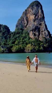 İki aşık, Railay kumsalının yumuşak kumlarında el ele romantik bir yürüyüş yapmayı sever. Yükselen kayalıkların ve berrak turkuaz suların çarpıcı arka planı mükemmel bir cennet ortamı yaratır..