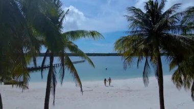 Koh Mak 'ın el değmemiş kıyılarında yürüyen iki arkadaş, sakin atmosferin ve çarpıcı manzaranın tadını çıkarıyor. Berrak palmiye ağaçları ve berrak sular rahatlama ve macera için mükemmel bir zemin oluşturur..