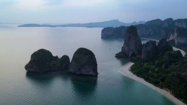 Güneş çarpıcı sahil şeridinde batarken Krabi Tayland 'ın dingin güzelliğine tanık olun. Görkemli kireçtaşı kayalıkları zümrüt sularından çıkar ve doğa aşıkları için sakin bir kaçış yaratır..