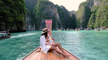 Krabi Tayland 'ın turkuaz sularında süzülen sakin bir kaçış gerçekleşir. Pileh Lagoon, Koh Phi Adası 'nda uzun kuyruklu bir teknenin önünde bir kadın.