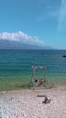İki arkadaş, Hırvatistan 'ın Brac Adası' ndaki güneşli bir sahilde sakin bir günün keyfini çıkarırken, turkuaz sularda hafif hafif sallanırken, çarpıcı doğal güzellikler ve uzak dağlarla çevrili..