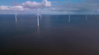 Hollanda 'da deniz aşırı türbinlerin yenilenebilir enerjiyi kullanan dingin güzelliğini keşfedin. Görkemli yapılar, sürdürülebilir bir geleceği simgeleyen mavi gökyüzüne karşı dimdik dururlar..