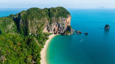 Railay Sahili, Krabi Tayland 'da yumuşak kumlar berrak sularla buluşur. Yükselen uçurumlar ve yemyeşil alanlarla çevrili bu huzurlu cennet, macerayı ve rahatlamayı davet ediyor.