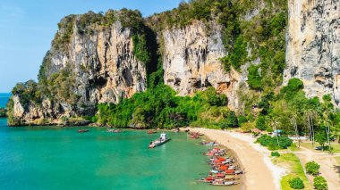Turkuaz suların yavaşça kıyıya vurması Tonsai Sahili 'nde sakin bir ortam yaratır. Krabi Tayland 'daki bu tropik cenneti keşfetmek için kıyıya yanaşan uzun kuyruklu tekneler var. 