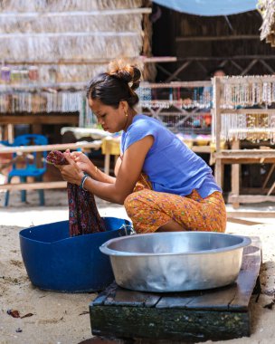 Phangnga, Tayland, 21 Ocak 2025, yerel bir Moken kadını Surin Adası 'ndaki sakin bir açık hava ortamında renkli kumaşları ustalıkla yıkıyor..