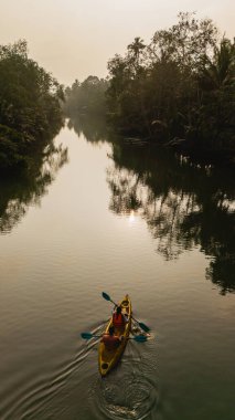 Tek bir kanocu, Tayland 'ın Chumphon kentindeki yemyeşil sularda sorunsuzca süzülür. Sabah ışığı sakin bir atmosfer yaratır..