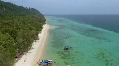 Yumuşak kumların turkuaz denizle buluştuğu Koh Kradan Adası 'nın huzurlu kıyılarını keşfedin. Huzurlu güzelliğe tanık olun, yerel tekneler sakin manzarayı noktalarken ve yemyeşil alanlar ufku süslerken..