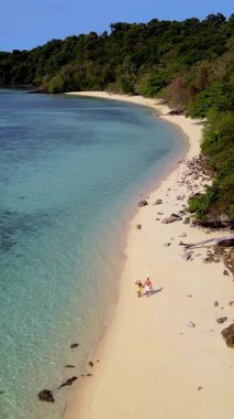 İki birey kristal berrak sular ve yemyeşil yeşilliklerle çevrili Koh Krada Tayland 'ın yumuşak kumlu kıyılarında rahatça yürüyor. Huzurlu ortam macera ve sükuneti davet ediyor..