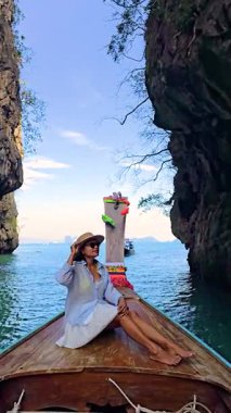 Bir gezgin, Tayland 'da nefes kesici kireçtaşı uçurumları ve kristal berrak sularla çevrili sakin bir tekne yolculuğunun tadını çıkarıyor. Krabi Koh Hong Adası 'nda uzun kuyruklu teknedeki Taylandlı kadın.
