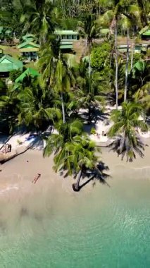 Tayland 'da sakin bir plajın tadını çıkarın, hafif dalgalar kıyıya vuruyor ve rüzgarda sallanan canlı palmiyeler. Koh Kood Adası