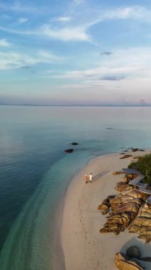Tayland 'ın sakin kıyılarında, yumuşak dalgalar kumsala vururken rahatlayın. Güneş canlı bir gökyüzünde batıyor, huzurlu bir geri çekilme için mükemmel sakin bir atmosfer yaratıyor Koh Munnork Adası
