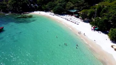 Tayland 'daki Koh Samet Adası' nın büyüleyici kıyılarını keşfedin yumuşak beyaz kumların turkuaz sularla buluştuğu. Sahile gidenler güneşin altında dinlenirken diğerleri ferahlatıcı bir dalış yapıyor..