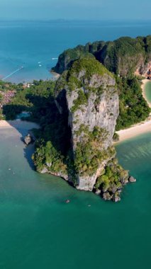 Tayland, Krabi 'nin büyüleyici manzaralarında dolaşın, orada yüksek uçurumlar turkuaz sularla buluşur. Huzurlu plajlar ve yemyeşil manzaralar keşfedin, Railay Sahili drone hava manzarası 