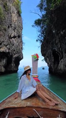Bir gezgin, Tayland 'daki nefes kesici kireçtaşı kayalıklarıyla çevrili geleneksel bir teknede huzurlu bir anın tadını çıkarır. Krabi 'deki Koh Hong Adası' nda uzun kuyruklu bir teknenin önünde bir kadın.