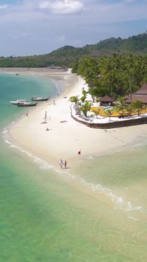 Koh Mook Adası 'nın altın kumları boyunca gezinirken hafif dalgalar ayaklarına kapanıyor. Güneşli bir günde bu tropikal cennetin yemyeşil ve çarpıcı manzarasını tecrübe edin..