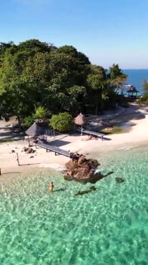 Tayland 'da sakin bir plajın göz kamaştırıcı manzarası yumuşak kumlar, canlı turkuaz sular ve yemyeşil tropikal bitki örtüsü. Yalnız bir figür Koh Munnork 'ta güneşin altında sakin bir ortamın tadını çıkarıyor.