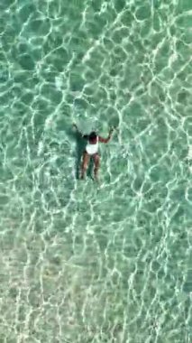 Tayland 'ın el değmemiş turkuaz sularında yüzen bir kadının büyüleyici dalgalarla çevrili görüntüsü. Koh Munnork Adası
