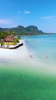 Tayland 'daki Koh Mook Adası' nın büyüleyici kıyılarını keşfedin, yumuşak beyaz kumların kristal berrak sularla buluştuğu. Çiftler ve aileler bu saklı cennetin huzurlu güzelliğinin tadını çıkarıyorlar..