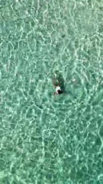 Sakin bir hava görüntüsü Tayland 'ın berrak turkuaz sularında huzur içinde yüzen birini yakalar. Koh Munnork Adası 'nda yüzen Taylandlı bir kadının drone görüntüsü.