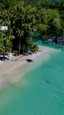 Koh Kood Tayland 'daki sakin plajlarda yumuşak kum, canlı turkuaz su ve sallanan palmiye ağaçları bulunur. Bir yüzücü, parlak mavi gökyüzünün altında ferahlatıcı okyanusun tadını çıkararak mükemmel bir cennet yaratır..