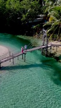 Koh Kood Tayland 'ın doğal güzelliğini, berrak suların üzerindeki kırsal bir köprüde gezinen çiftler olarak yaşayın. Bereketli yeşillik bu sakin tropikal kaçışı çevrelemiş, rahatlamak için mükemmel..